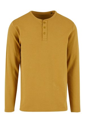 Senfgelbe Langarm-Henley-Bluse mit einer Drei-Knopf-Leiste und rundem Ausschnitt, aus geribbeltem Stoff gefertigt.