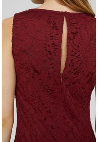 Bordeaux kanten top met intricaten bloemmotieven, een sleutelgatrug met ritsluiting en textuurstof. Mouwloos ontwerp.