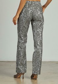 Zilveren metallic broek met een bloemenkant patroon en een rechte snit. De stof heeft een gestructureerde glans, gecombineerd met strappy hoge hakken.