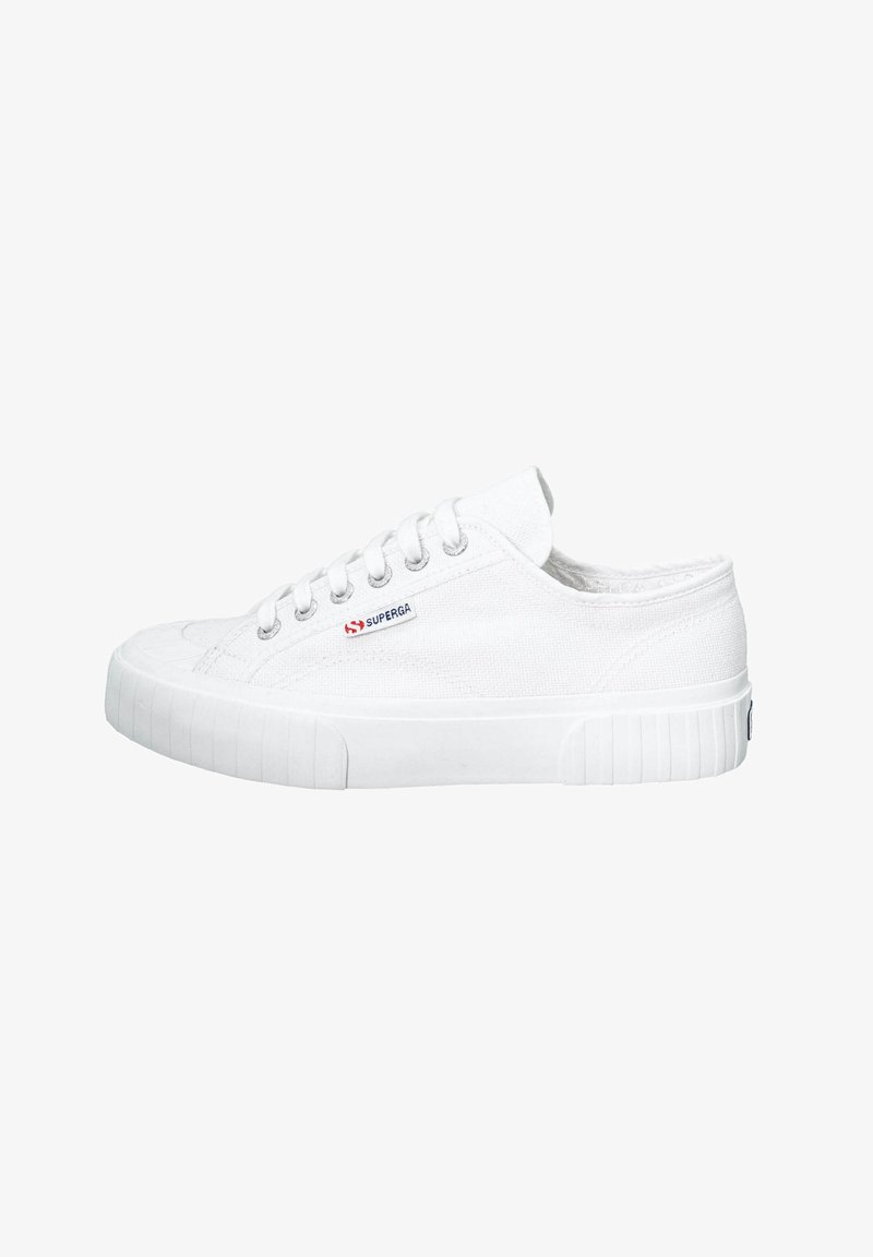 Witte canvas sneaker met ronde neus, gestructureerde bovenkant en platte rubberen zool. Beschikt over zes gaatjes en een logo patch aan de zijkant.