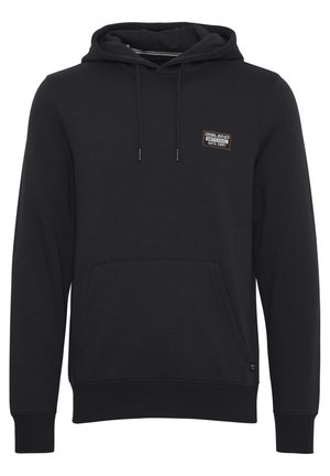 Svart hoodie av mjukt tyg, med en ficka fram, justerbar dragkedja på huvan och en liten märkespatch på bröstet.