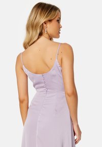 Abito di raso lavanda con scollatura a barchetta, spalline sottili e dettaglio con bottoni nascosti lungo la schiena. Tessuto liscio e silhouette aderente.