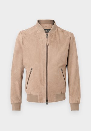 Veste bomber en daim beige avec fermeture éclair frontale, deux poches latérales zippées, poignets côtelés et ourlet côtelé.