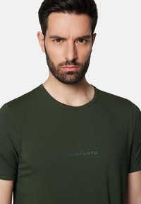 Oliwkowy t-shirt z okrągłym dekoltem, krótkimi rękawami i gładką teksturą. Posiada małe, niebieskie haftowane logo "LANCERTO" na piersi.