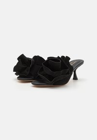 Sorte semskede mules har overdimensjonerte svarte stoffblomster foran, åpen tå-design og en slank høy hæl.
