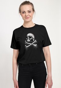 Svart t-shirt med en central grafik av ett skalle-och-korsben i grått, med droppande detaljer, på en slät bomullstextur.
