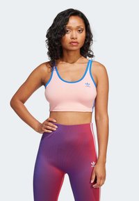 Růžová sportovní podprsenka s modrým lemem a malým logem, spárovaná s gradientními legínami v purpurové a růžové barvě s bílými pruhy a detaily loga.
