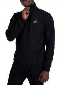 Zwarte fleece sweater met een hoge kraag, kwart ritssluiting en geborduurd logo op de borst. Ribgebreide manchetten en zoom, zachte textuur.