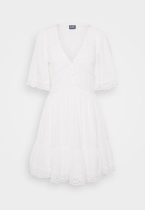 Vestido blanco con mangas cortas, escote en V, frente abotonado y falda en capas. Presenta un borde de ojal y una tela suave y texturizada.