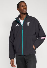 Μαύρο αθλητικό μπουφάν με πετρόλ φερμουάρ, που φέρει το λογότυπο L.F.C. και ροζ λεπτομέρειες στα μανίκια. Κατασκευασμένο από ελαφρύ ύφασμα, με άνετη γραμμή.