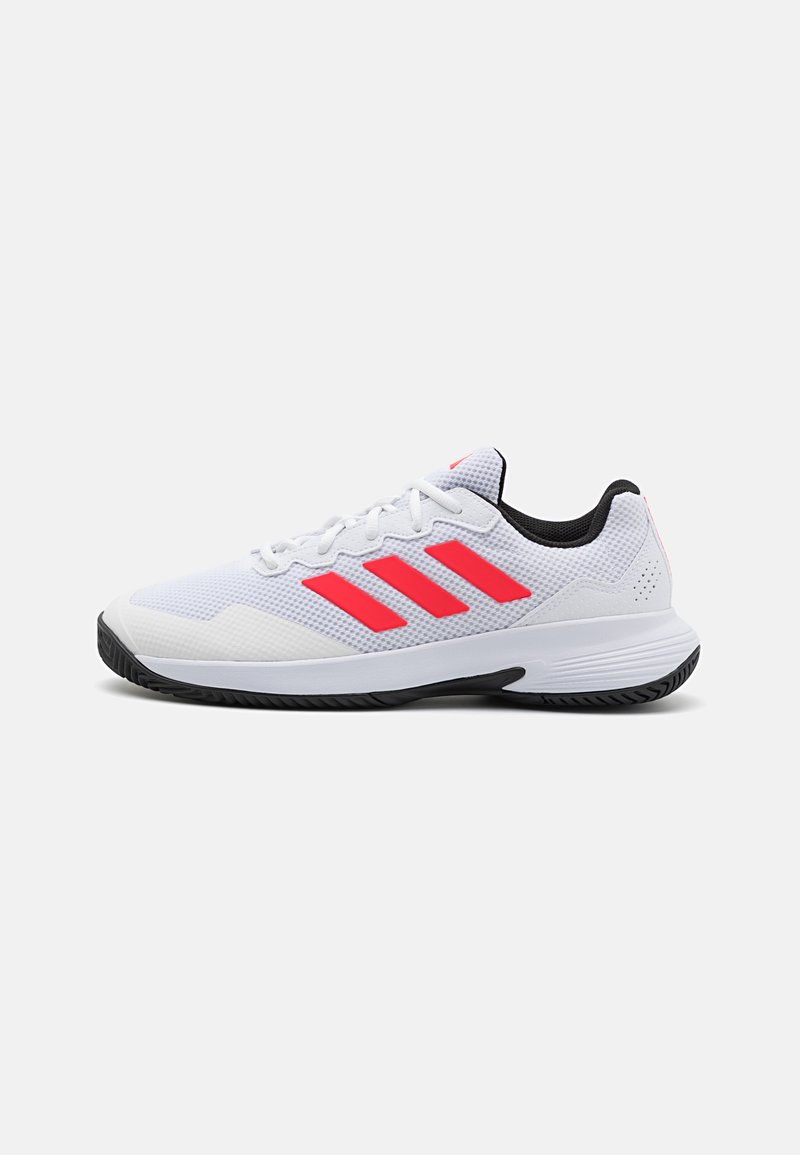 Chaussure de sport blanche avec un matériau en maille, des accents roses et un design à trois bandes. Elle présente un intérieur noir et une semelle en caoutchouc texturée.