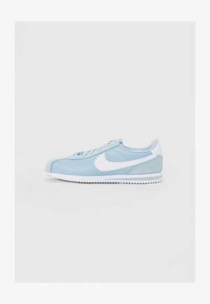 Lyseblå sneakers med hvite detaljer, mesh- og semsket skinnmaterialer, rund tå, flat hvit såle, og mønster med tekstur.