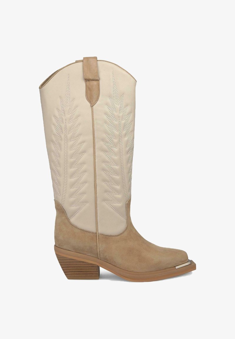 Bota vaquera marrón con sección inferior de ante y parte superior beige, que presenta patrones de hojas en relieve y un tacón de madera apilada.