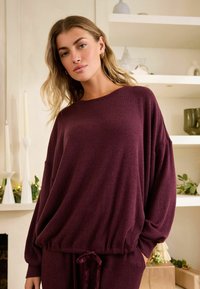 Bordeaux-ribbet sweatshirt med en afslappet pasform, lange ærmer og en snoretræk i kanten. Tekstureret stof med en blød overflade.