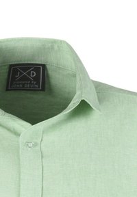 lichtgroen button-up shirt met een gestructureerde kraag, zachte textuur, en een label met de tekst "JXD gepresenteerd door JOHN DEVIN" dat zichtbaar is aan de binnenkant.