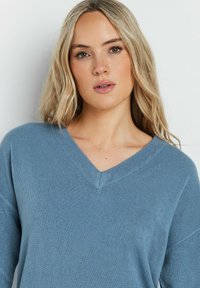 Blauer Strickpullover mit V-Ausschnittdesign. Verfügt über lange Ärmel und eine weiche Textur, ideal für legere Anlässe.