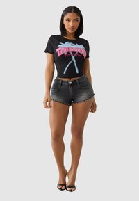 Black cropped t-shirt with "True Religion" graphic in pink and blue, paired with high-waisted black denim shorts featuring frayed hem.