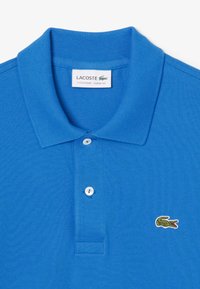 Blå bomullspolo t-shirt med klassisk passform, kort krage, tvåknäppning och en grön Lacoste-logotyp broderad på bröstet.