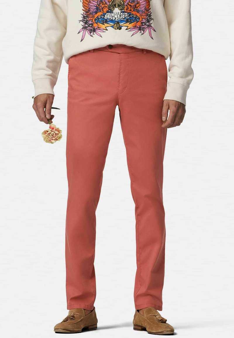 Chinos rose clair avec une coupe slim, en coton. Associés à un sweatshirt graphique beige et des mocassins marron. Fleurs tenues à la main droite.