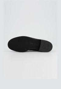 Suela de zapato de goma negra con superficie texturizada. Presenta la marca "paul green" y un diseño de tacón redondeado. Plana, funcional y duradera.