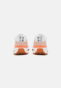 Sportliche Sneakers aus pinkem Wildleder und metallischem Silber. Dicke weiße Sohle mit einem orangen Akzent. Abgerundete Form, gepolsterte Knöchelunterstützung.