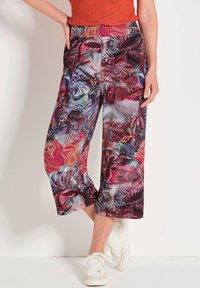 Pantalons cropped colorés avec un motif floral et de feuilles vif dans des tons rouges, violets et bleus, fabriqués en tissu léger.