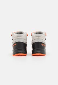 Zapatos de senderismo grises y negros con acentos naranjas. Diseño de media caña, parte superior texturizada, cuello acolchado y suela de goma duradera.