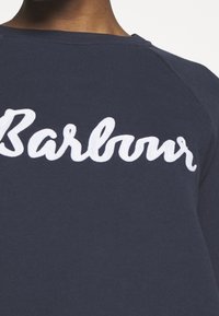 Námořnická modrá mikina s bílým vyšitým textem "Barbour" na přední straně, s kulatým výstřihem a raglánovými rukávy z hladkého materiálu.