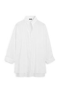 Blouse blanche à manches longues avec col montant et boutons dissimulés sur le devant, avec ourlet double épaisseur et poignets retroussés.