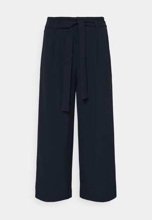 Marineblaue weit geschnittene Hose mit hoher Taille und einem vorne gebundenen Stoffgürtel, vor einfachem Hintergrund präsentiert.