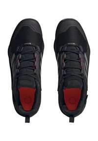 Czarne buty sportowe z siateczkowym wierzchem, wzmocnionym czubkiem, czerwonymi akcentami i odblaskowymi detalami. Oferują wyściełaną wkładkę oraz sznurowany fason.