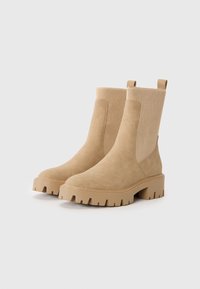 Bottines en daim tan avec des panneaux latéraux en tissu côtelé, semelles à crampons épaisses et languettes. Texture lisse avec un design à bout rond.