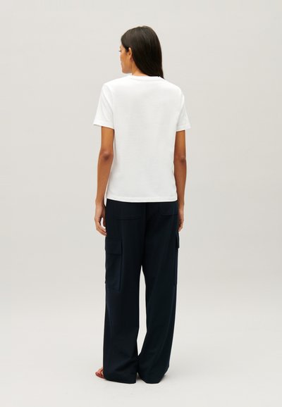 T-shirt blanc à manches courtes associé à un pantalon cargo large bleu marine avec poches latérales et une coupe décontractée.