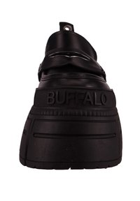 Black platform sneaker with a textured rubber sole, featuring a wide strap and metal accents. Brand name "BUFFALO" embossed on the side.