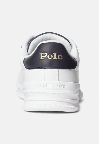 Desportivo branco com detalhe em pele azul-marinho no calcanhar, com a palavra "Polo" em letras douradas e "RalphLauren" gravado na sola. Textura suave.