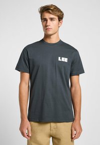 Mörkgrå bomull t-shirt med rund halsringning och korta ärmar, med en vit "LEE" logotyp tryckt på vänster bröst.