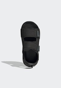 Sort sandal med to justerbare velcro-remme, perforeret fodseng for åndbarhed, flad sål, og minimal branding på hælen.
