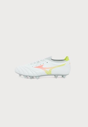 Witte voetbalschoen met geel-oranje verlooplogo, veterluiting en plastic noppen onder de zool voor grip op grasvelden.