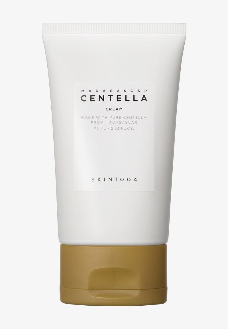 Weißer Tubus mit Madagaskar-Centella-Creme, der einen goldenen Boden aufweist. Das Etikett gibt deutlich den Produktnamen und die Größe an, mit minimalistischen Designelementen.