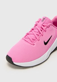 Baskets de sport Nike roses avec une tige en mesh respirant, logo Swoosh noir, lacets plats, semelle rembourrée et design à bout rond.