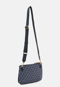 Navy-blue crossbody bag in textile material with a geometric pattern, gold-tone hardware, and adjustable strap. Zippered closure at top.