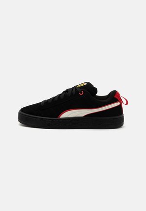 Czarny niski sneaker z białym paskiem, czerwoną zakładką na pięcie, czarną podeszwą i czarnymi sznurowadłami na jednolitym jasnym tle.