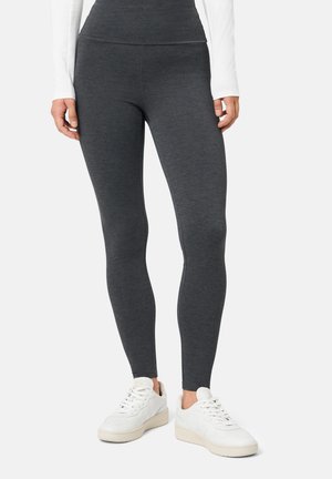Graue Leggings mit hohem Bund aus dehnbarem Stoff, mit glatter Textur und figurbetontem Schnitt. Kombiniert mit weißen Sneakern.