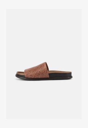 Rudos tekstūros atviros šlepetės su plačia diržele ir juodu padu ant paprasto šviesiai pilko fono.