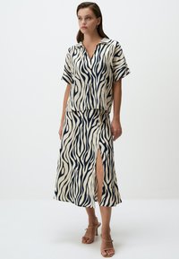 Ensemble en deux pièces à imprimé zèbre en crème et marine. Comprend un haut à col et à manches courtes ainsi qu'une jupe assortie avec une fente sur le côté. Tissu texturé.