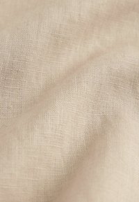 Hellbeige Leinenstoff mit feiner, strukturierter Webart, sanftem Fall und subtiler Glanz, der natürliche Fasern und leicht unregelmäßige Stellen zeigt.