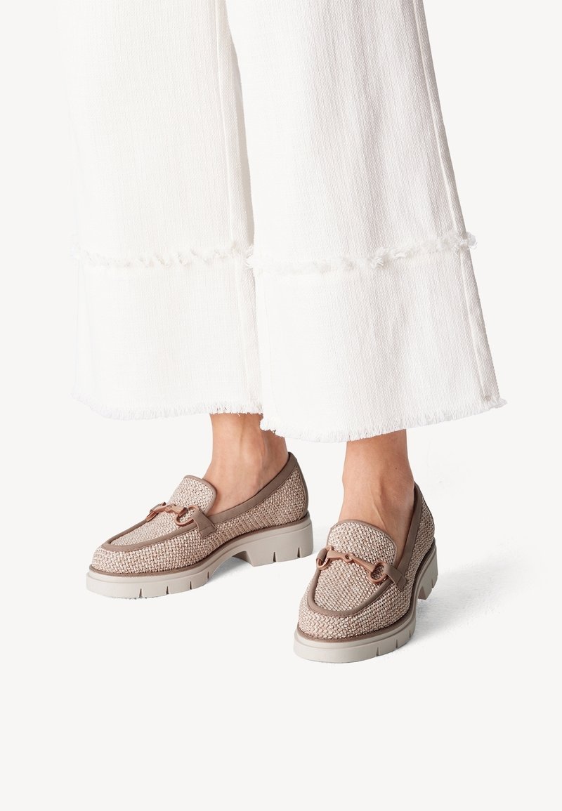 Mocassins tissés beige avec semelles blanches épaisses portés avec un pantalon blanc à jambes larges se terminant au-dessus des chevilles.