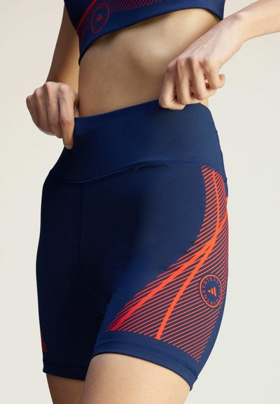 Navy blue athletic shorts with red diagonal stripes, high waistband, stretch fabric, and a circular logo on the lower left side.