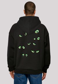 Čierna mikina s kapucňou so veľkou grafikou rôznych zelených očí na chrbte, s rôznymi tvarmi a výrazmi. Nastaviteľná kapucňa s šnúrkou.