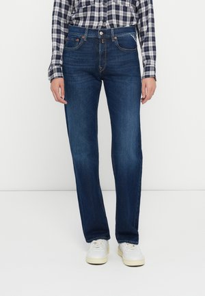 Donkerblauwe denim jeans met een rechte pijp, voorzien van voorzakken en een knoopsluiting. De stof vertoont lichte vervaging.